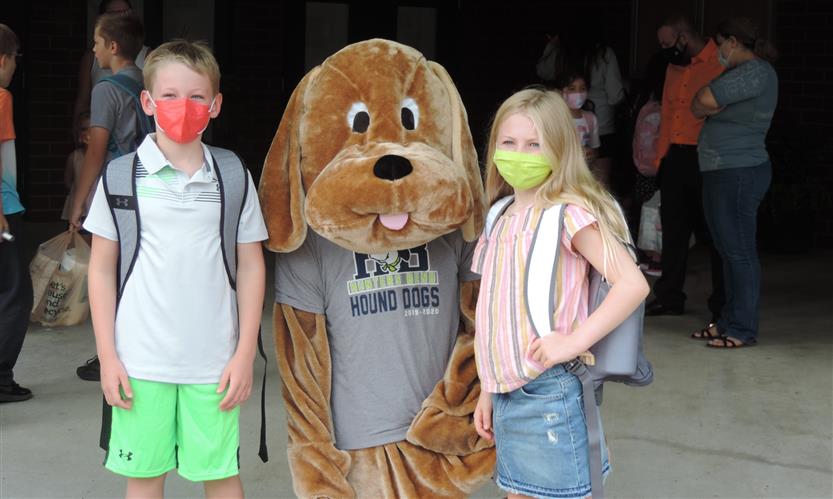 Two students take a photo with a dog mascot